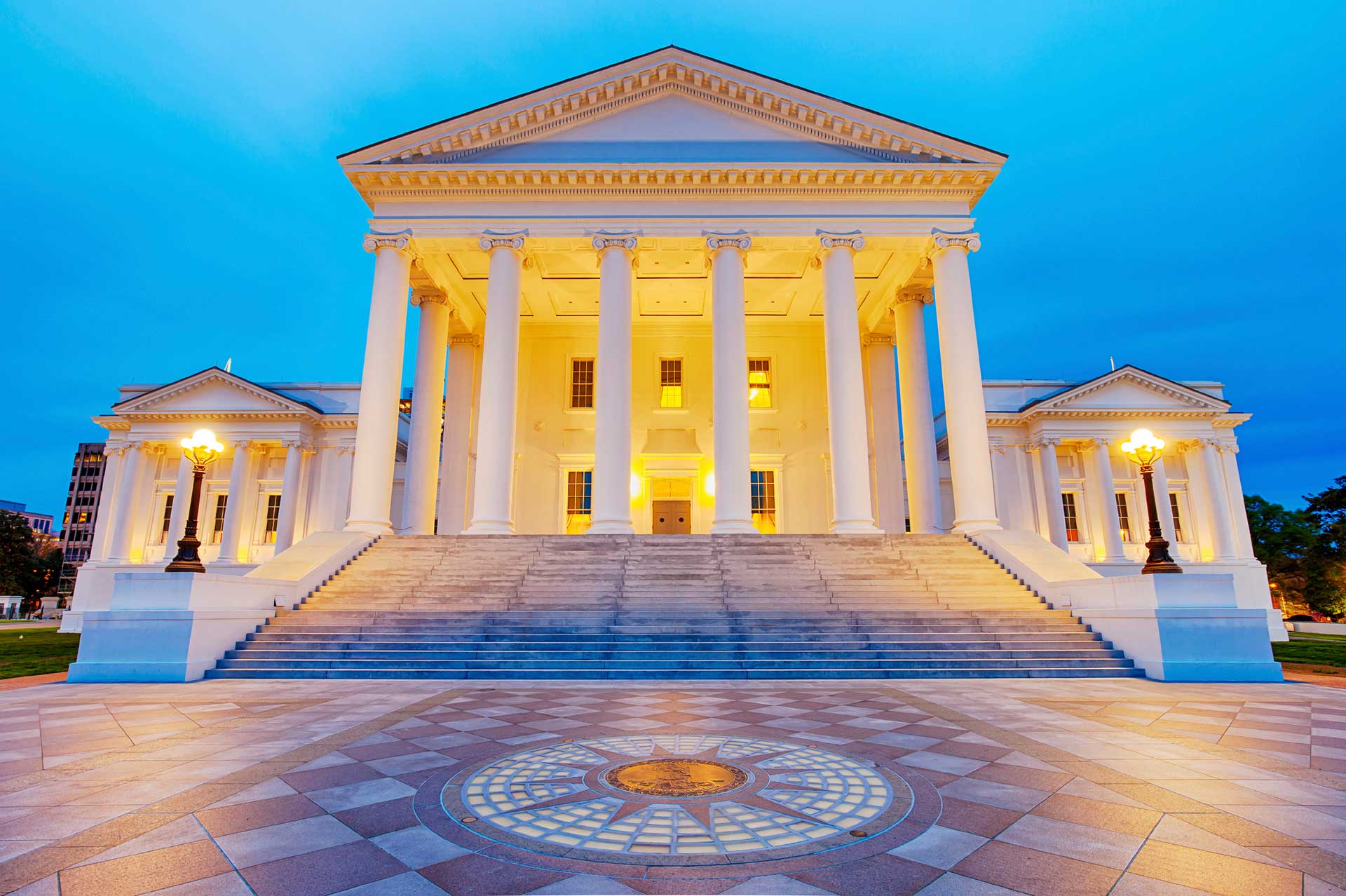 Virginia State Capitol building at dusk with lights on and wide front steps.