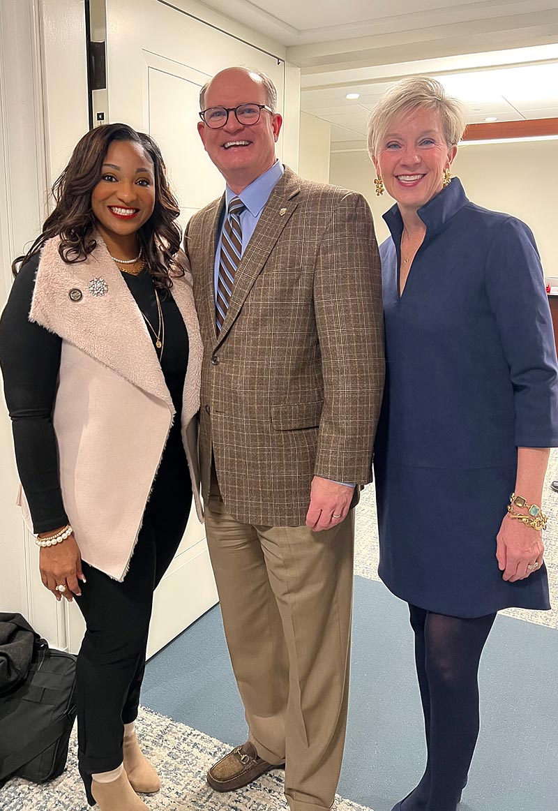 Susan Gaston with two colleagues standing together in a modern office, engaged in conversation and collaboration.